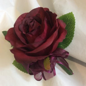 A buttonhole featuring a single burgundy silk rose