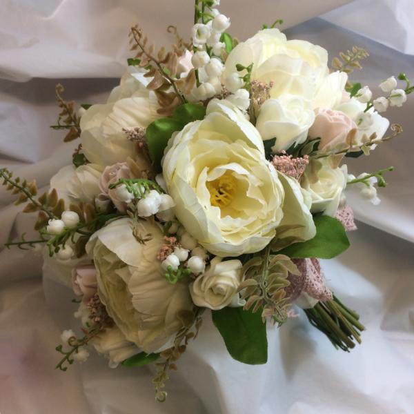 a wedding bouquet featuring dusky pink and ivory peonies roses and lily of the valley
