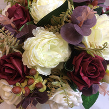 An artificial flower arrangement in shades of ivory and burgundy