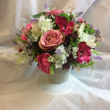 A table centre featuring artificial pink and cream flowers