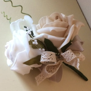 A corsage featuring foam roses in shades of beige, ivory and white