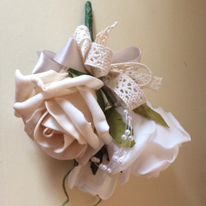 A corsage featuring foam roses in shades of beige, ivory and white