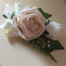 A corsage featuring foam roses in shades of ivory and latte