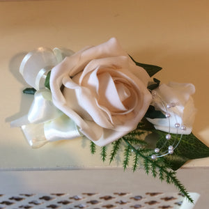 A corsage featuring foam roses in shades of ivory and latte