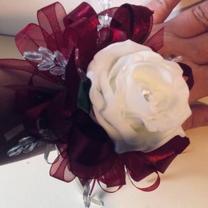 A wrist corsage featuring a single foam rose, ribbon and crystal leaves