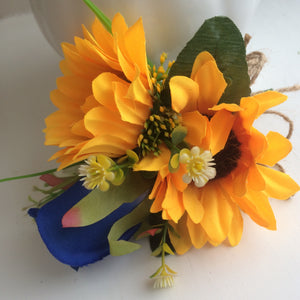 A corsage featuring two yellow sunflowers & royal blue silk rose