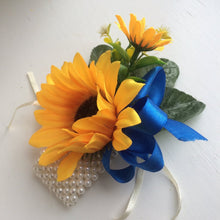 a wrist corsage of yellow sunflowers and royal blue ribbon