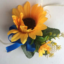 A wrist corsage featuring a yellow sunflowers on an ivory pearl bracelet