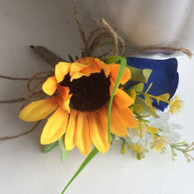 A corsage featuring a yellow sunflower & royal blue silk rose