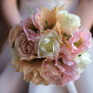 A wedding bouquet featuring peach. pale pink & ivory flowers