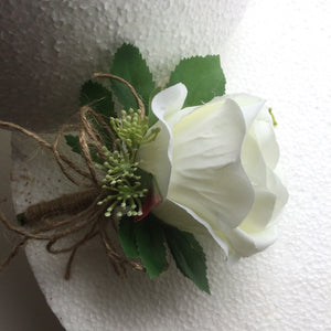 a buttonhole featuring lily of the valley & a white or ivory silk rose