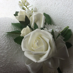 A corsage featuring lily of the valley & ivory foam roses