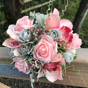 A wedding bouquet of coral and grey artificial roses and orchids