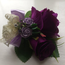 A corsage featuring artificial purple & lilac roses & vintage lace bow