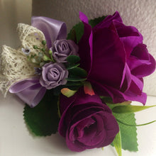 A corsage featuring artificial purple & lilac roses & vintage lace bow