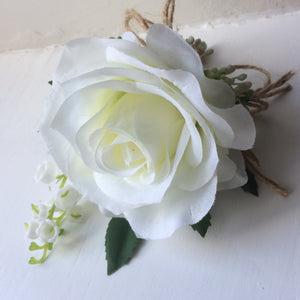 a buttonhole featuring lily of the valley & a white or ivory silk rose