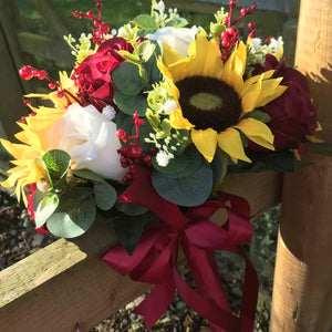 A wedding bouquet featuring berries, roses & sunflowers