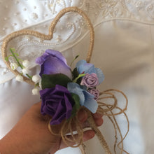 A rustic heart shaped wand with a cluster of purple and lilac flowers