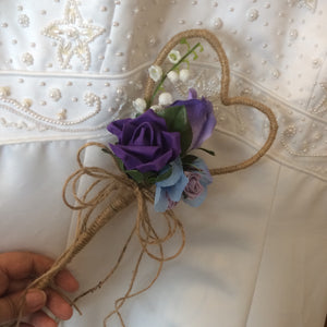 A rustic heart shaped wand with a cluster of purple and lilac flowers