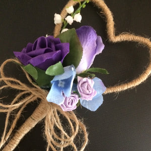 A rustic heart shaped wand with a cluster of purple and lilac flowers