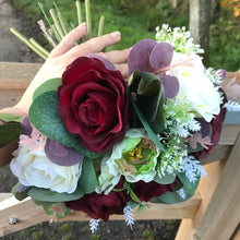 A brides bouquet of deep burgundy and ivory faux flowers
