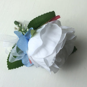 a silk buttonhole featuring a single open white rose