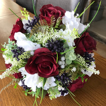 A wedding bouquet of artificial silk burgundy & ivory flowers, foliage & berries