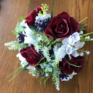 A wedding bouquet of artificial silk burgundy & ivory flowers, foliage & berries