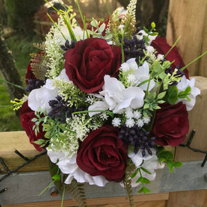 A wedding bouquet of artificial silk burgundy & ivory flowers, foliage & berries