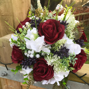 A wedding bouquet of artificial silk burgundy & ivory flowers, foliage & berries