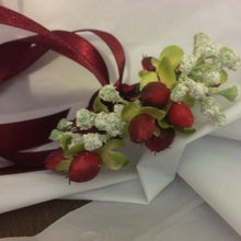 A wrist corsage featuring a hypericium berries and gypsophila
