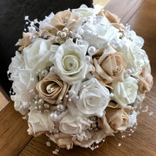 An artificial wedding bouquet featuring beige, white and ivory foam roses