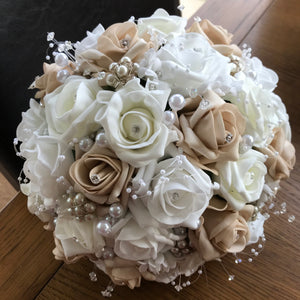 An artificial wedding bouquet featuring beige, white and ivory foam roses