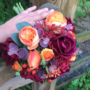 A wedding bouquet of artificial silk burgundy & orange flowers
