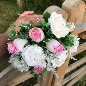 An artificial wedding bouquet featuring pink and white roses