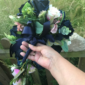 A teardrop bouquet of artificial navy and blush roses