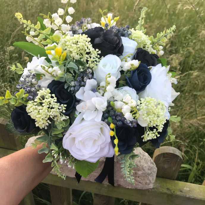 A bridal bouquet of navy blue and ivory flowers