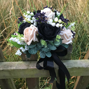 A bridal bouquet of white, black, beige and ivory artificial flowers