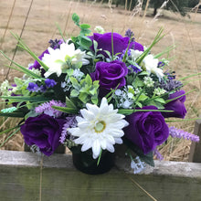 a grave pot with cream and purple artificial silk blooms