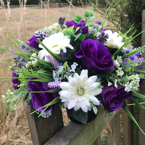 a grave pot with cream and purple artificial silk blooms