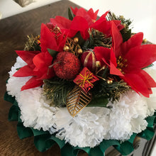 a memorial Christmas grave side posy of red poinsettia cones baubles and carnations
