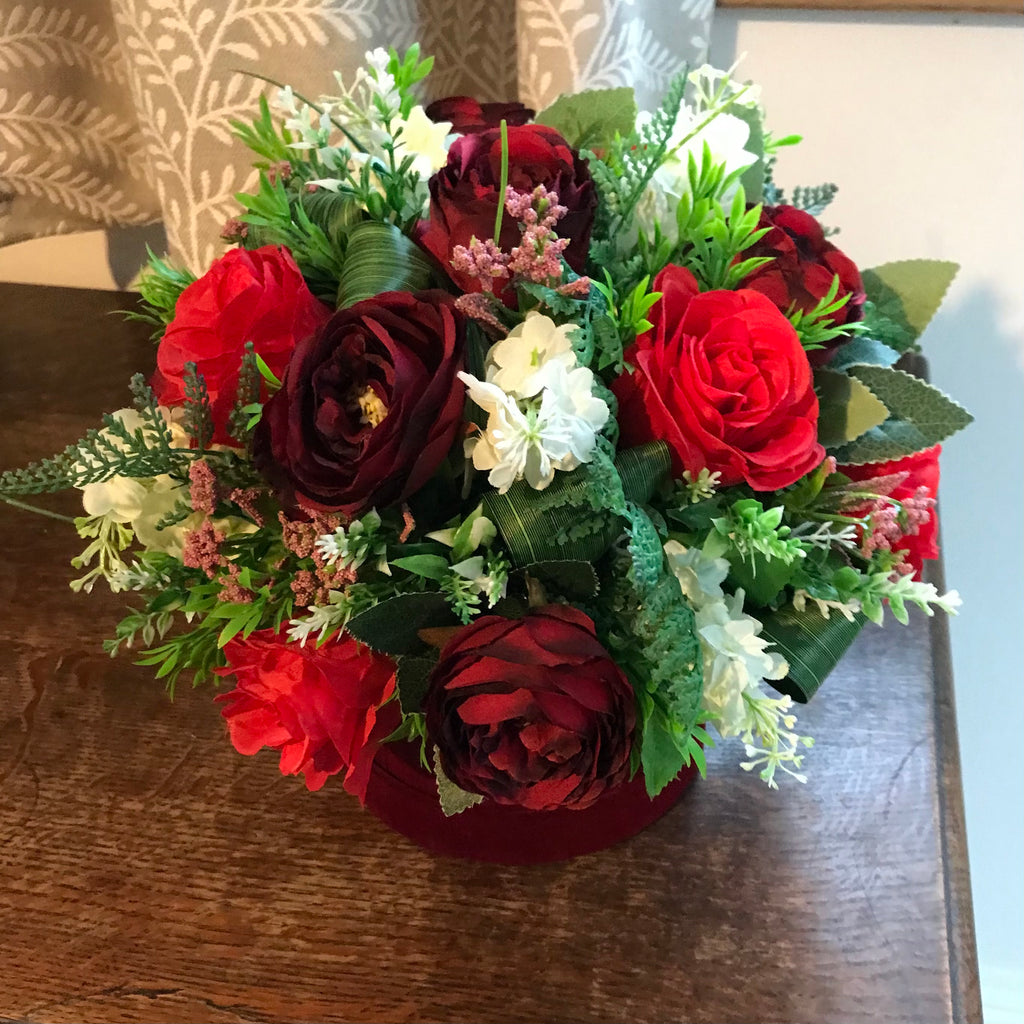 A flower arrangement of red artificial flowers in velvet hat box ...