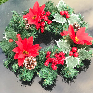 an artificial pine christmas wreath with holly and cones
