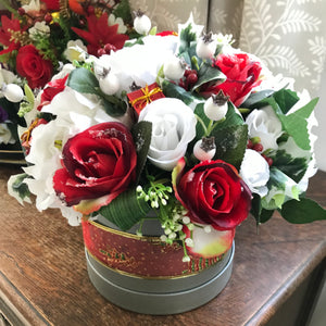 A Christmas flower arrangement featuring artificial white and red roses