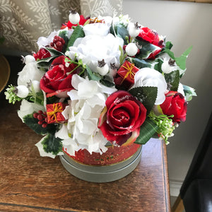 A Christmas flower arrangement featuring artificial white and red roses