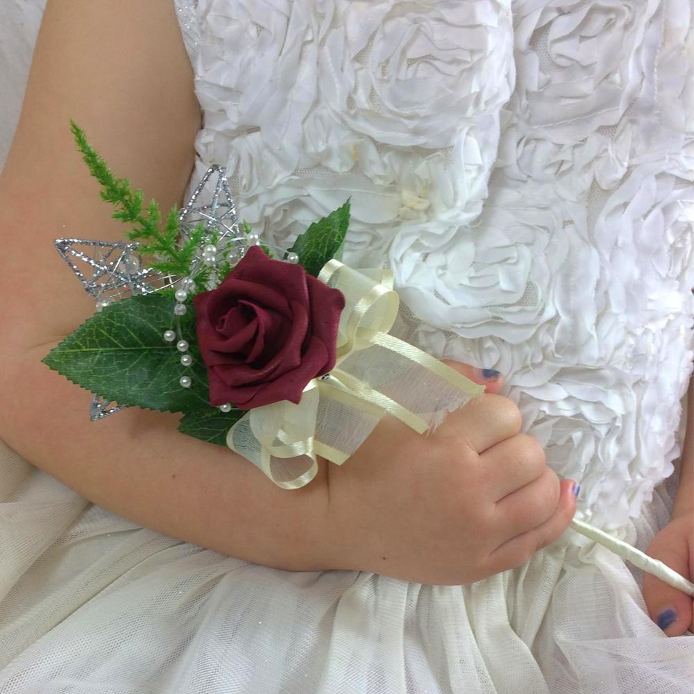 a burgundy rose and cream ribbon decorate a silver metal wand