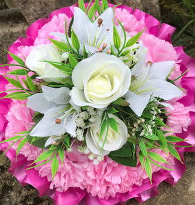a funeral posy of artificial silk roses and lilies in shades of pink and white