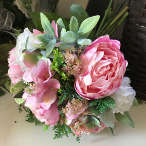 A brides bouquet of artificial pink peonies and ivory roses