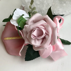 A pink corsage featuring calla lily and roses