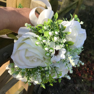 A brides wedding bouquet of artificial silk ivory roses and daisies